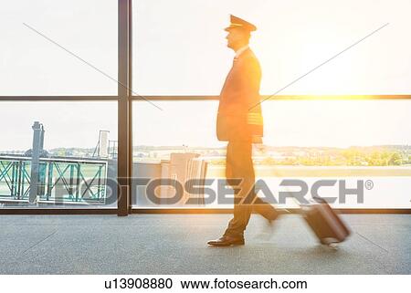 Portrait of mature pilot walking in airport with yellow lens flare View Large Photo Image Stock Image - Portrait of mature pilot walking in airport with yellow lens flare . Fotosearch