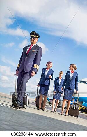 Portrait of mature pilot walking with three young beautiful flight attendants against airplane in airport View Large Photo Image Picture - Portrait of mature pilot walking with three young beautiful flight attendants against airplane in airport. Fotosearch