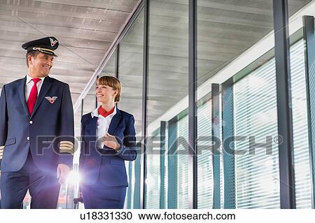 Portrait of mature pilot walking with young attractive stewardess in airport View Large Photo Image Stock Image - Portrait of mature pilot walking with young attractive stewardess in airport. Fotosearch