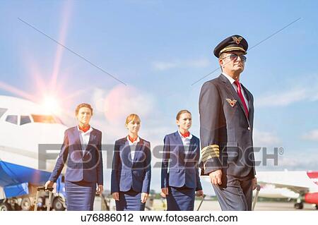 Portrait of mature pilot walking with three young beautiful flight attendants against airplane in airport View Large Photo Image Stock Image - Portrait of mature pilot walking with three young beautiful flight attendants against airplane in airport. Fotosearch
