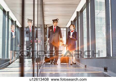 Portrait of mature pilot walking with young attractive stewardess in airport View Large Photo Image Stock Photo - Portrait of mature pilot walking with young attractive stewardess in airport. Fotosearch