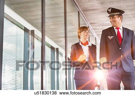 Portrait of mature pilot walking with young attractive stewardess in airport View Large Photo Image Stock Photo - Portrait of mature pilot walking with young attractive stewardess in airport. Fotosearch