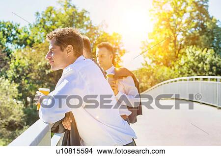 Portrait of mature thoughtful attractive businessman drinking coffee while standing on the bridge with colleagues View Large Photo Image Picture - Portrait of mature thoughtful attractive businessman drinking coffee while standing on the bridge with colleagues . Fotosearch