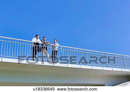 Portrait of mature thoughtful attractive businessman drinking coffee while standing on the bridge with colleagues View Large Photo Image Stock Photo - Portrait of mature thoughtful attractive businessman drinking coffee while standing on the bridge with colleagues . Fotosearch