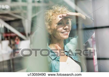 Portrait of mature woman covering her eyes from sunlight while looking through the window in airport View Large Photo Image Stock Image - Portrait of mature woman covering her eyes from sunlight while looking through the window in airport. Fotosearch