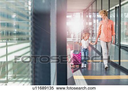 Portrait of mature woman walking with her daughter in arrival area at airport with lens flare View Large Photo Image Stock Photography - Portrait of mature woman walking with her daughter in arrival area at airport with lens flare . Fotosearch