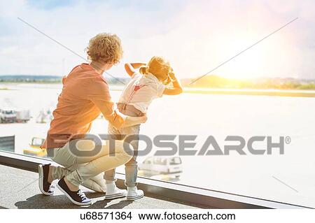 Picture - Portrait of mature woman with her cute little daughter looking through the window in airport. Fotosearch