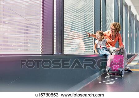 Portrait of mature woman with her cute little daughter looking through the window in airport View Large Photo Image Stock Image - Portrait of mature woman with her cute little daughter looking through the window in airport. Fotosearch