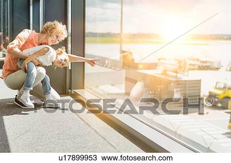 Portrait of mature woman with her cute little daughter looking through the window in airport View Large Photo Image Stock Image - Portrait of mature woman with her cute little daughter looking through the window in airport. Fotosearch