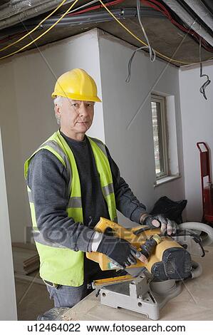 Stock Image - Portrait of middle-aged worker at construction site. Fotosearch