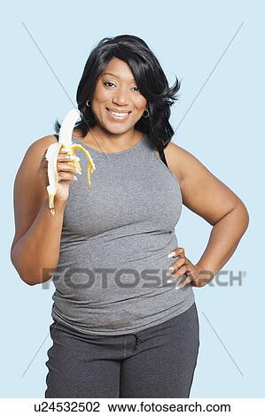 Portrait of mixed race woman holding banana over blue background View Large Photo Image Stock Image - Portrait of mixed race woman holding banana over blue background. Fotosearch