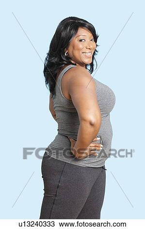 Portrait of mixed race woman with hand on hip exercising over blue background View Large Photo Image Stock Image - Portrait of mixed race woman with hand on hip exercising over blue background. Fotosearch