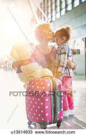 Portrait of mother reuniting and kissing her daughter on forehead in airport View Large Photo Image Stock Image - Portrait of mother reuniting and kissing her daughter on forehead in airport. Fotosearch