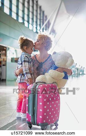 Portrait of mother reuniting and kissing her daughter on forehead in airport View Large Photo Image Stock Photo - Portrait of mother reuniting and kissing her daughter on forehead in airport. Fotosearch