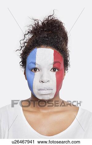 Stock Image - Portrait of sad young African American woman with French flag painted on face against white background. Fotosearch