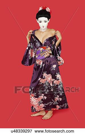 Stock Photo - Portrait of seductive Japanese woman in kimono standing against red background. Fotosearch