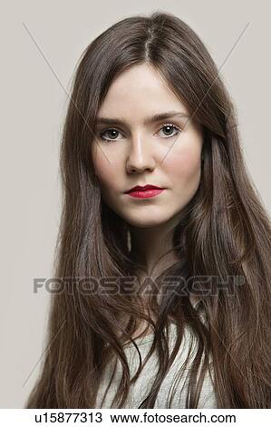 Stock Image - Portrait of sensuous young woman with red lips against gray background. Fotosearch