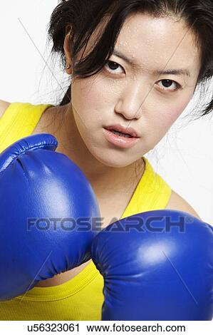Portrait of serious Asian woman wearing boxing gloves against white background View Large Photo Image Stock Image - Portrait of serious Asian woman wearing boxing gloves against white background. Fotosearch