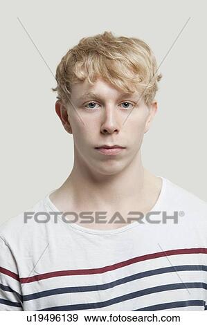 Stock Photo - Portrait of serious young man over gray background. Fotosearch