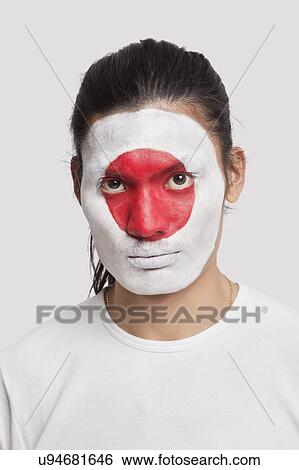 Stock Photograph - Portrait of serious young mixed race man with Japanese flag painted on face against white background. Fotosearch