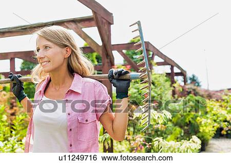 Portrait of smiling mature beautiful gardener holding fork rake View Large Photo Image Stock Photograph - Portrait of smiling mature beautiful gardener holding fork rake . Fotosearch