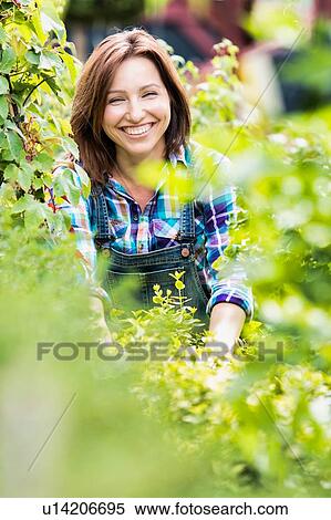 Portrait of smiling mature beautiful shop owner standing against plants View Large Photo Image Stock Photography - Portrait of smiling mature beautiful shop owner standing against plants. Fotosearch