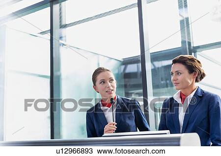 Stock Image - Portrait of smiling young attractive passenger service agent standing in airport. Fotosearch