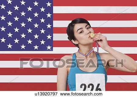 Portrait of smiling young female medalist standing against American flag View Large Photo Image Stock Photo - Portrait of smiling young female medalist standing against American flag. Fotosearch