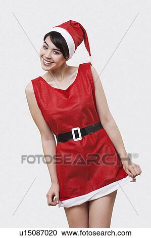 Stock Image - Portrait of smiling young woman in Santa outfit over white background. Fotosearch