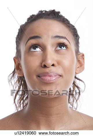 Stock Image - Portrait of smiling young woman looking up against white background. Fotosearch