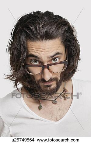 Picture - Portrait of suspicious young man wearing eyeglasses against white background. Fotosearch