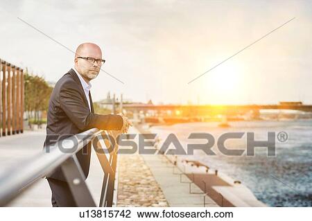 Portrait of thoughtful mature businessman leaning on railing View Large Photo Image Stock Image - Portrait of thoughtful mature businessman leaning on railing. Fotosearch