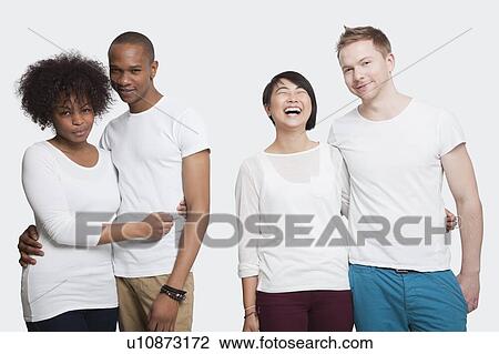 Stock Image - Portrait of two young couples in casuals standing together over white background. Fotosearch