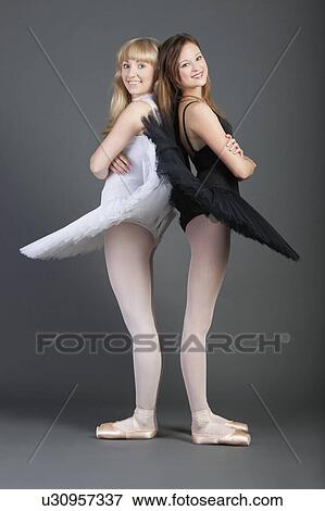 Stock Photo - Portrait of two young female ballet dancers standing back to back over grey background. Fotosearch