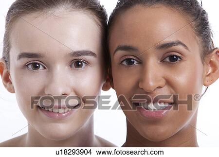 Portrait of two young female friends smiling together against white background View Large Photo Image Picture - Portrait of two young female friends smiling together against white background. Fotosearch