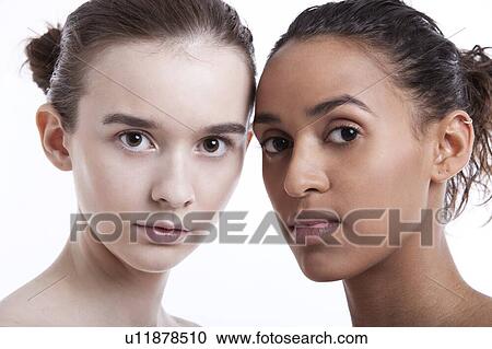 Stock Image - Portrait of two young women against white background. Fotosearch
