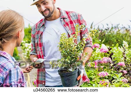 Stock Photography - Portrait of woman buying plant on a pot from gardener in shop. Fotosearch