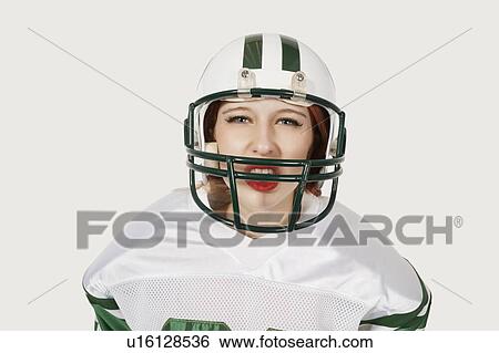 Stock Photograph - Portrait of woman in football uniform against gray background. Fotosearch