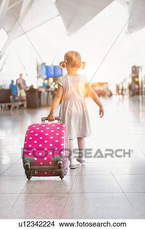 Picture - Portrait of young adorable little girl running in airport with her pink suitcase . Fotosearch