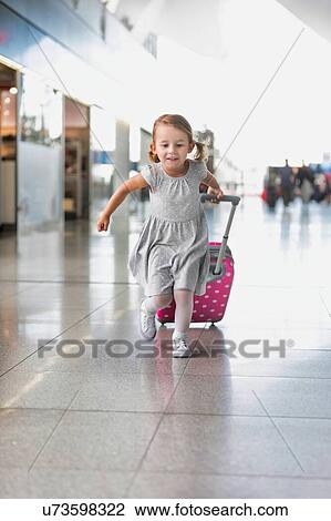 Portrait of young adorable little girl running in airport with her pink suitcase View Large Photo Image Stock Image - Portrait of young adorable little girl running in airport with her pink suitcase . Fotosearch