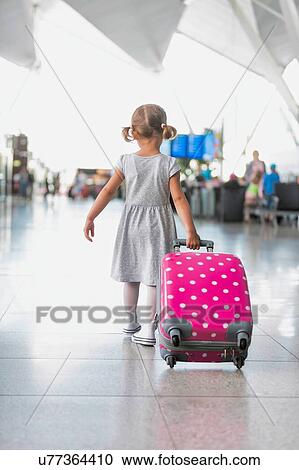 Portrait of young adorable little girl running in airport with her pink suitcase View Large Photo Image Stock Image - Portrait of young adorable little girl running in airport with her pink suitcase . Fotosearch