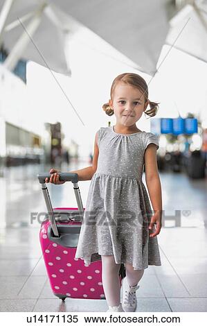 Stock Photography - Portrait of young adorable little girl running in airport with her pink suitcase . Fotosearch