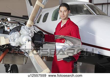 Stock Photo - Portrait of young aeronautic engineer standing in front of an airplane propeller. Fotosearch