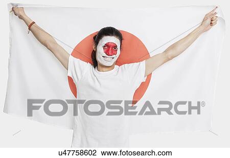 Stock Image - Portrait of young Asian man with Japanese flag smiling against white background. Fotosearch