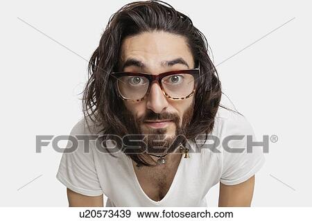 Stock Photo - Portrait of young Asian man with eyeglasses staring against white background. Fotosearch