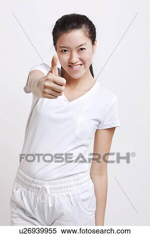 Portrait of young Asian woman gesturing thumbs up against white background View Large Photo Image Stock Photography - Portrait of young Asian woman gesturing thumbs up against white background. Fotosearch