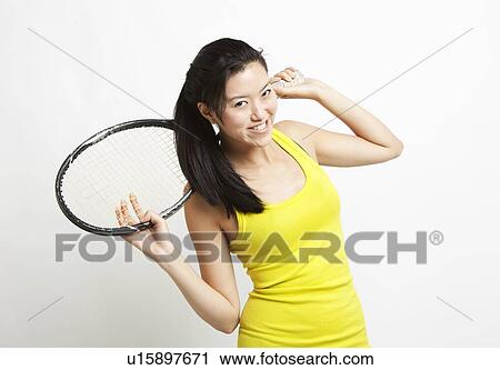 Portrait of young Asian woman holding tennis racket over her shoulder against white background View Large Photo Image Stock Image - Portrait of young Asian woman holding tennis racket over her shoulder against white background. Fotosearch