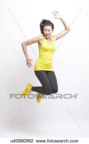 Portrait of young Asian woman in yellow tank top and leggings jumping against white background View Large Photo Image Stock Image - Portrait of young Asian woman in yellow tank top and leggings jumping against white background. Fotosearch
