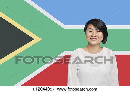 Stock Photo - Portrait of young Asian woman smiling against South African flag. Fotosearch