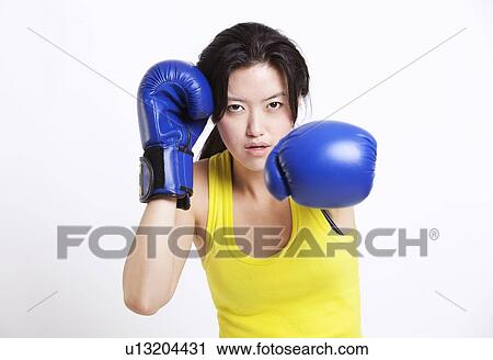 Portrait of young Asian woman wearing blue boxing gloves against white background View Large Photo Image Stock Image - Portrait of young Asian woman wearing blue boxing gloves against white background. Fotosearch